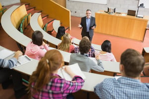 Elegant teacher with students sitting at the college lecture hall-1